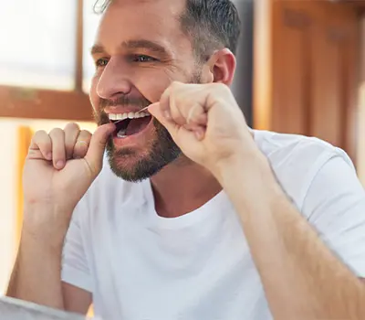 Man in white shirt flossing teeth