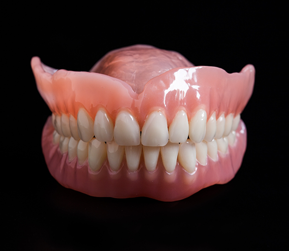 Set of full dentures against a black background