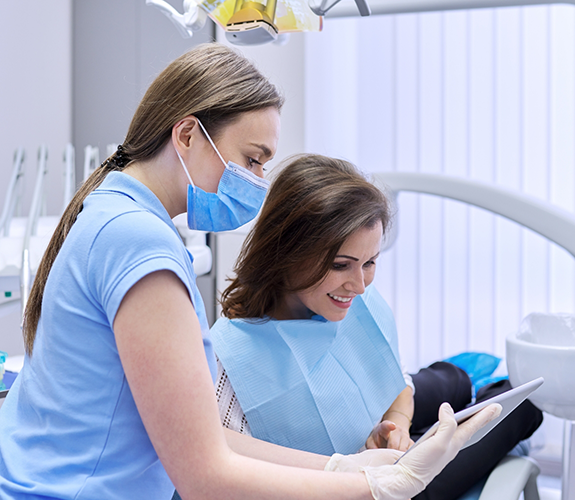 Dental team member showing a tablet to a patient in the dental chair