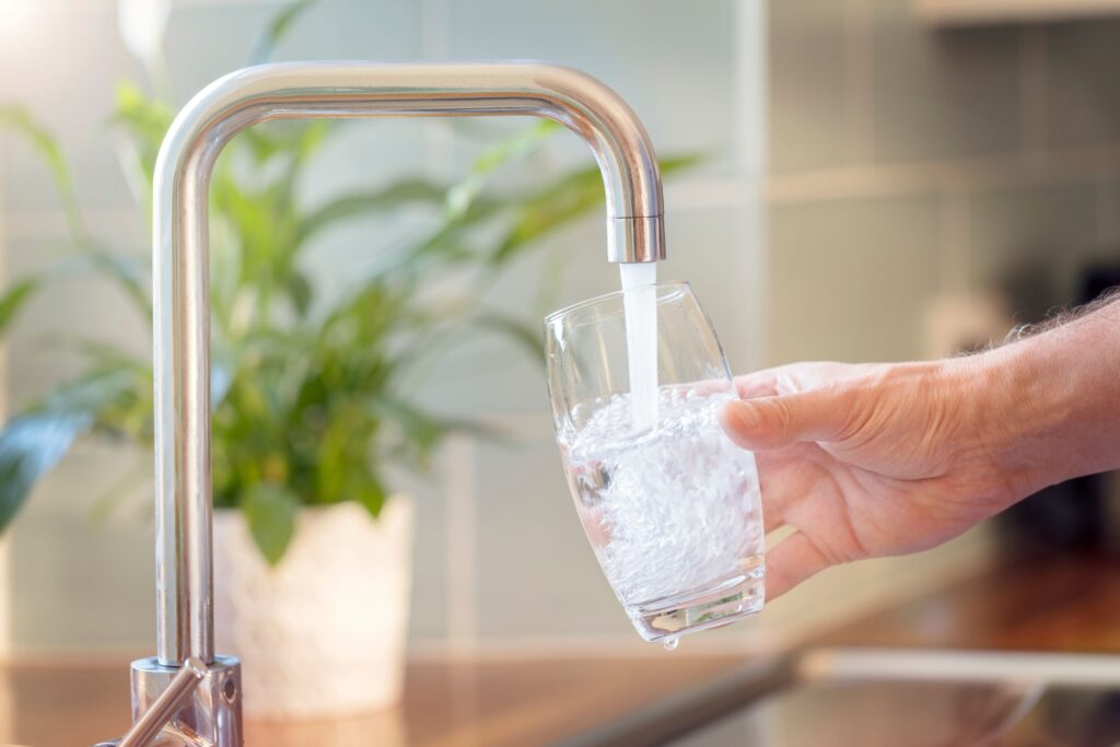 Hand holding glass under running tap water