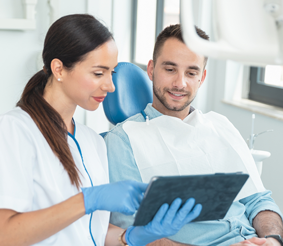 Dental professional showing a tablet screen to a patient in the dental chair