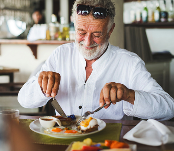 Senior man cutting up a plate of food