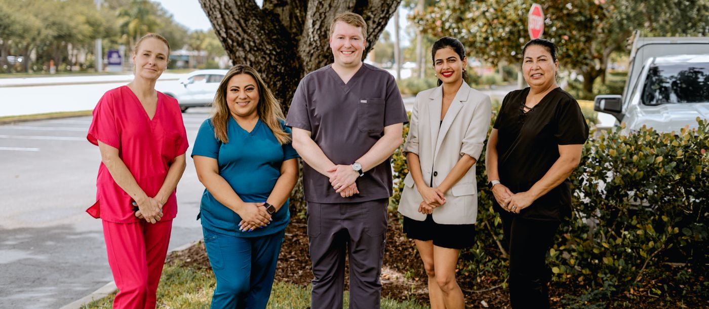 Stuart dentists and team members smiling in front of a tree
