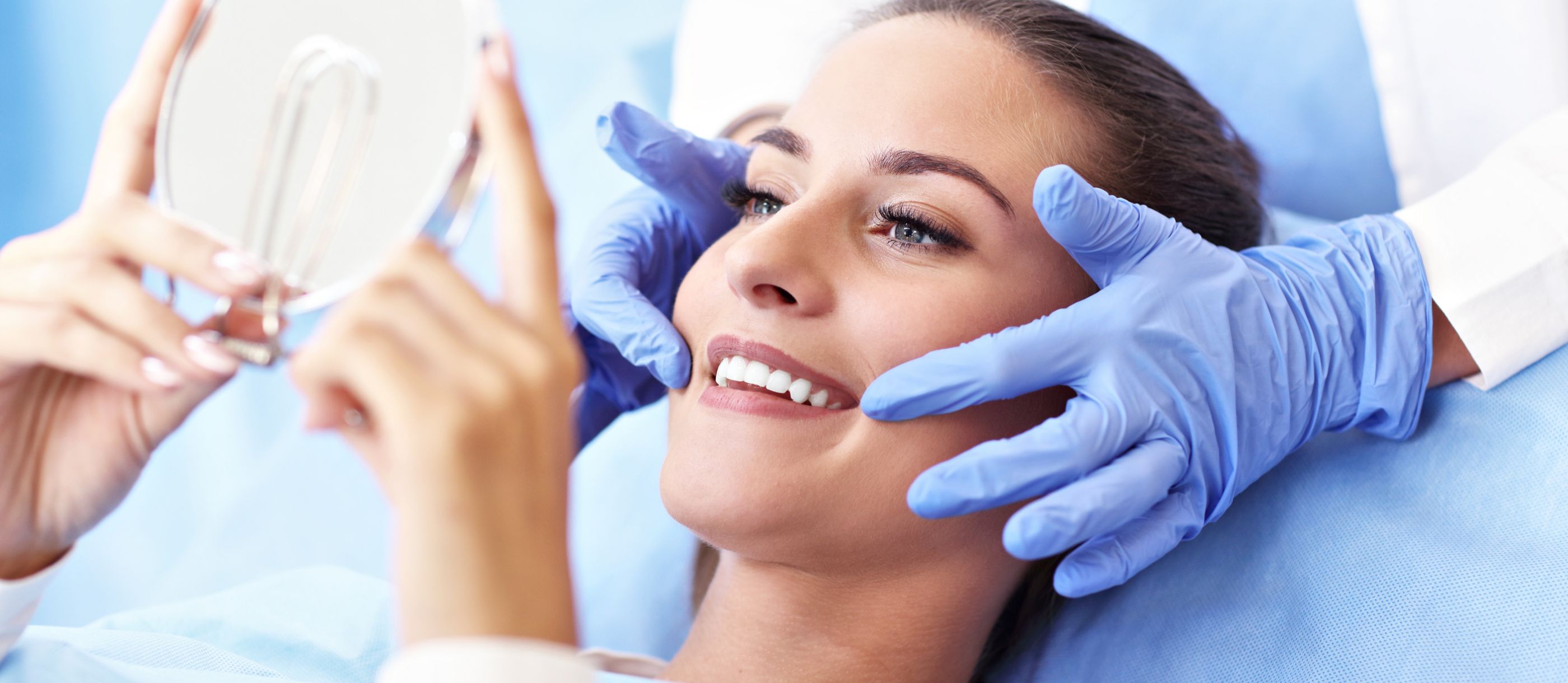 Woman looking at her smile in a mirror after restorative dentistry in Stuart