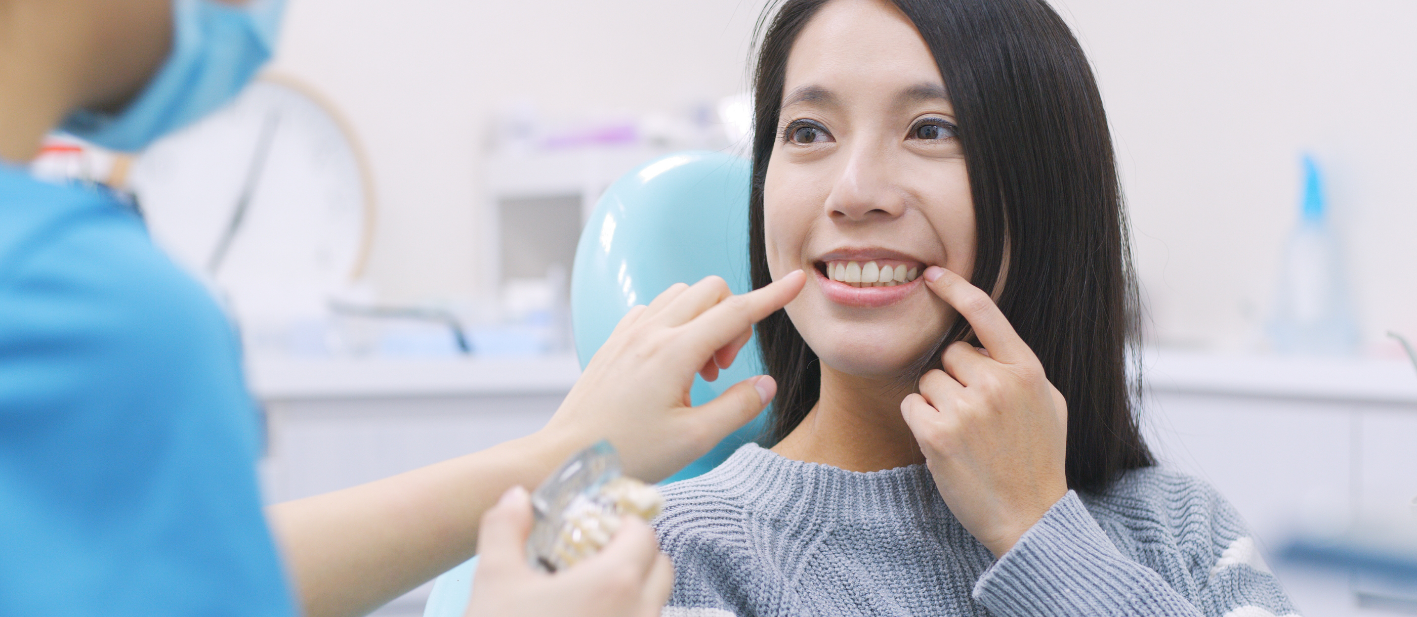 Woman in dental chair pointing to her smile before tooth extractions in Stuart